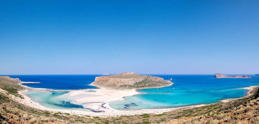 brown and green island on blue sea under blue sky during daytime