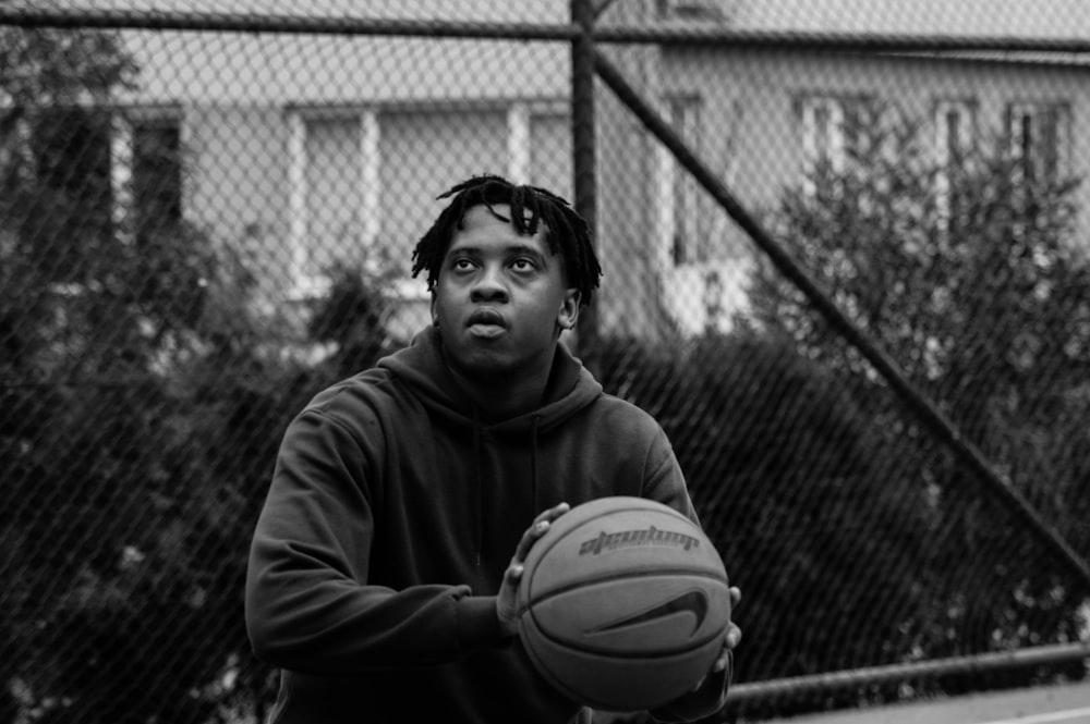 grayscale photo of man in hoodie holding basketball