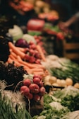 A vibrant display of fresh vegetables including radishes, carrots, leafy greens, and other produce neatly arranged. The scene is lively with a focus on natural textures and colors.