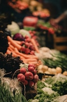 A vibrant display of fresh vegetables including radishes, carrots, leafy greens, and other produce neatly arranged. The scene is lively with a focus on natural textures and colors.