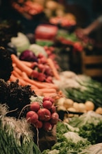 A vibrant display of fresh vegetables including radishes, carrots, leafy greens, and other produce neatly arranged. The scene is lively with a focus on natural textures and colors.