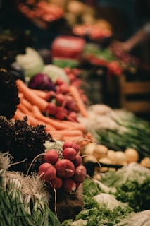 A vibrant display of fresh vegetables including radishes, carrots, leafy greens, and other produce neatly arranged. The scene is lively with a focus on natural textures and colors.