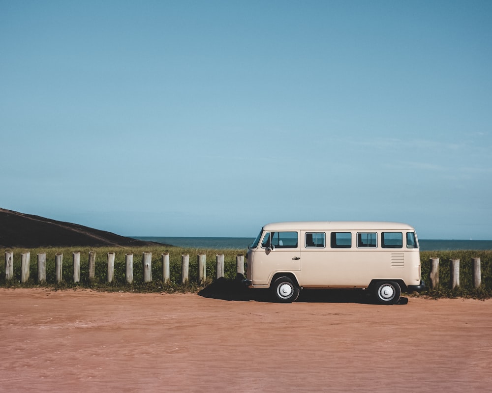 white and purple van on brown dirt road during daytime