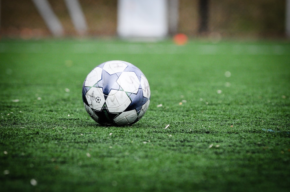 Ballon de football blanc et bleu sur un terrain en herbe verte pendant la journée