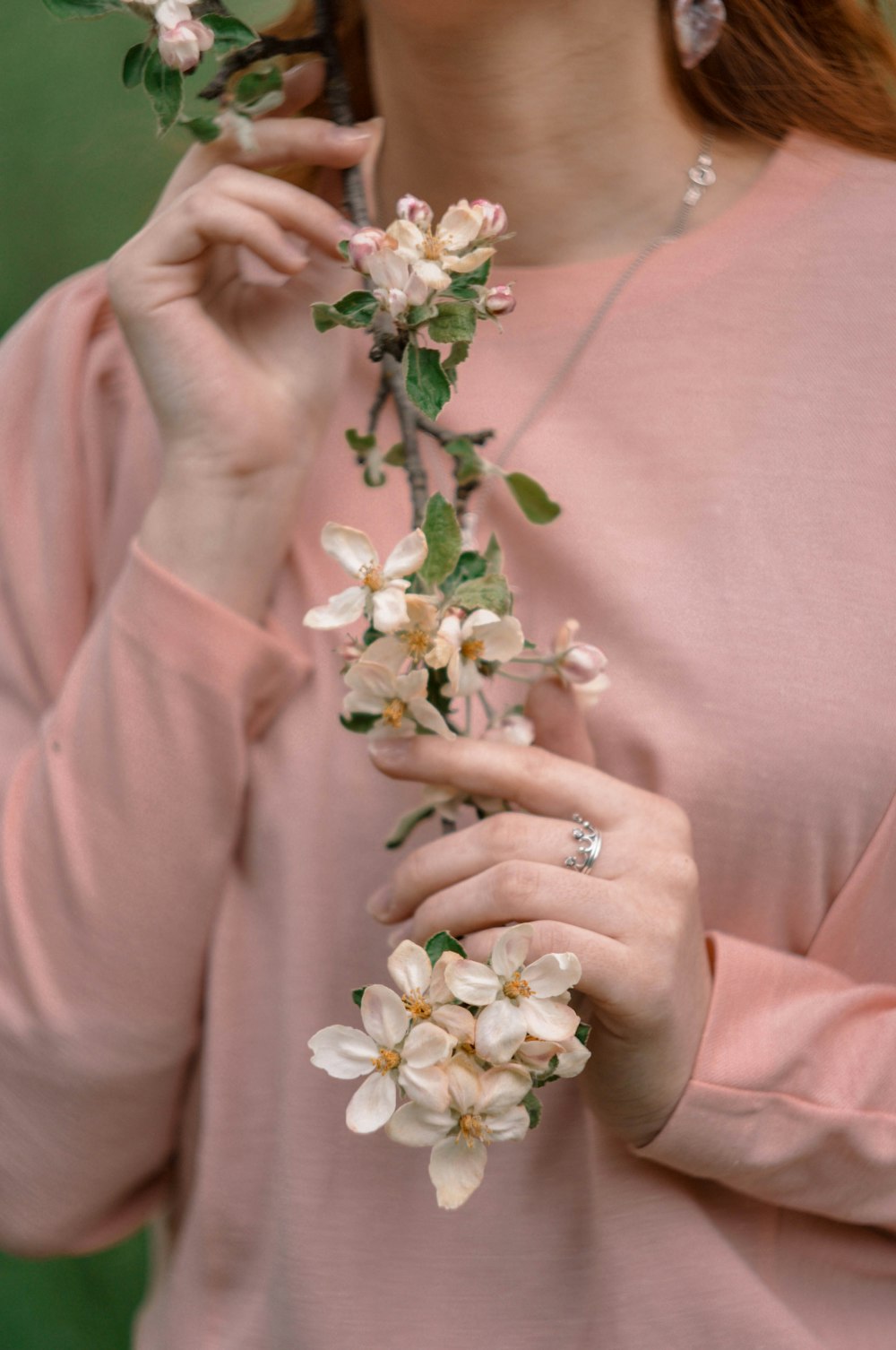 woman in pink long sleeve shirt holding white flowers