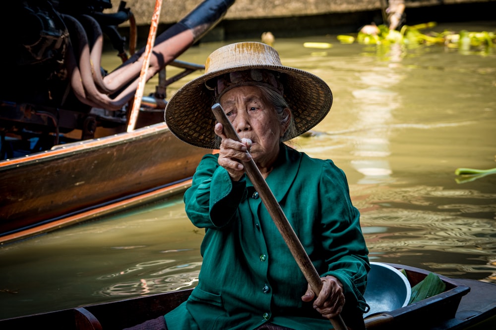 man in blue dress shirt wearing brown hat sitting on boat during daytime