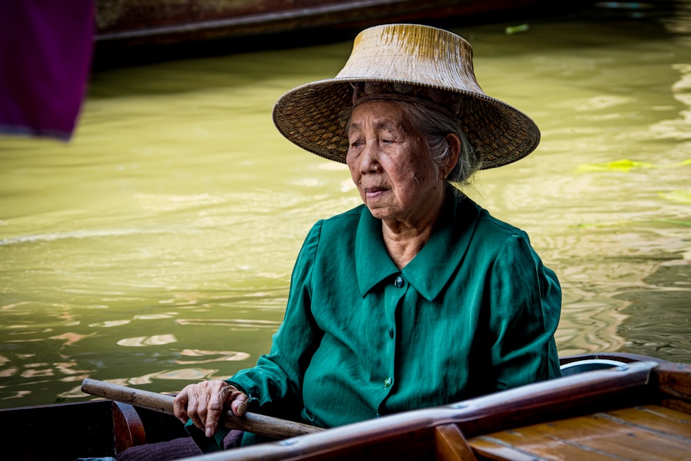 man in blue dress shirt wearing brown straw hat riding on boat during daytime