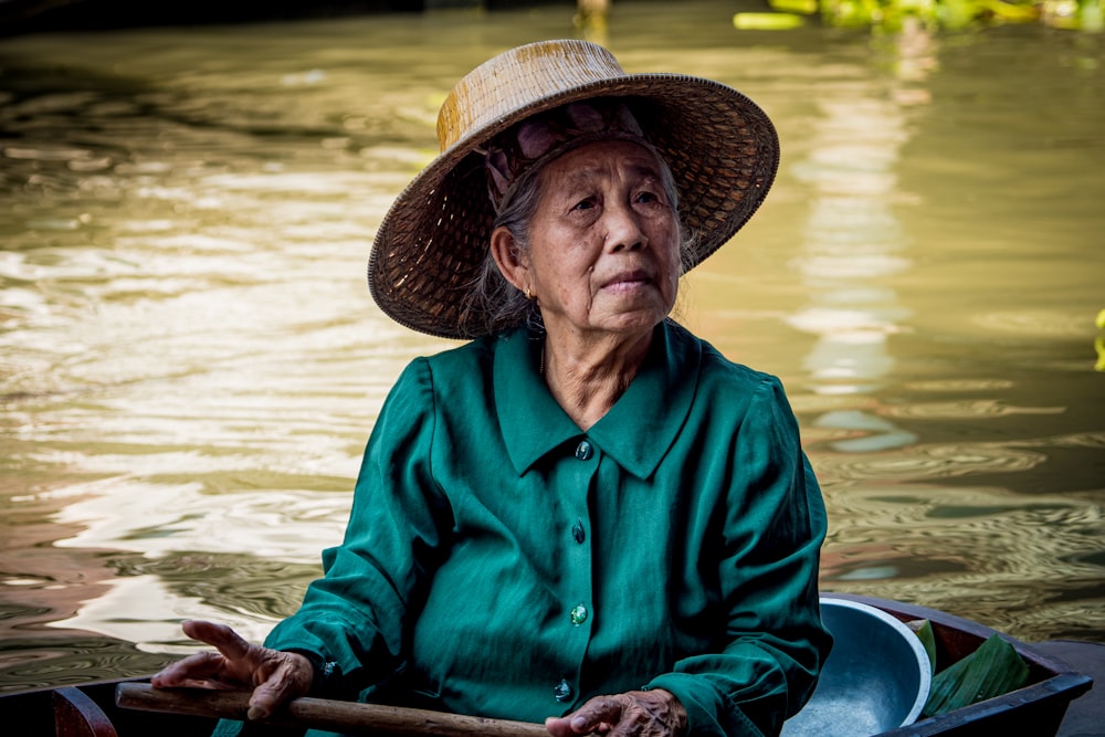 man in blue dress shirt and brown straw hat sitting on boat during daytime