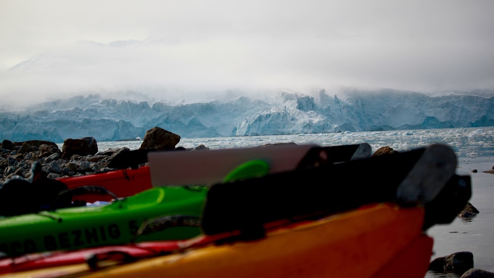 green and yellow kayak on shore near snow covered mountain during daytime