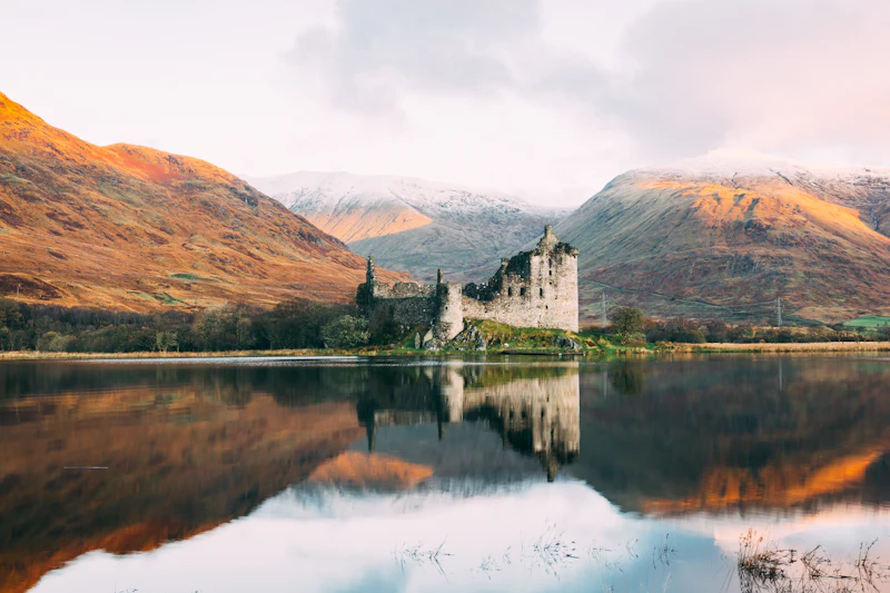 Stone building beside still water under a pale overcast sky