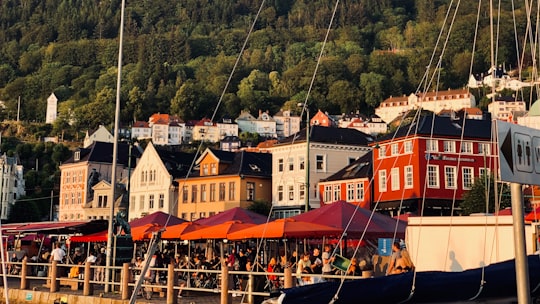 people riding on boat near houses during daytime in Fishmarket in Bergen Norway