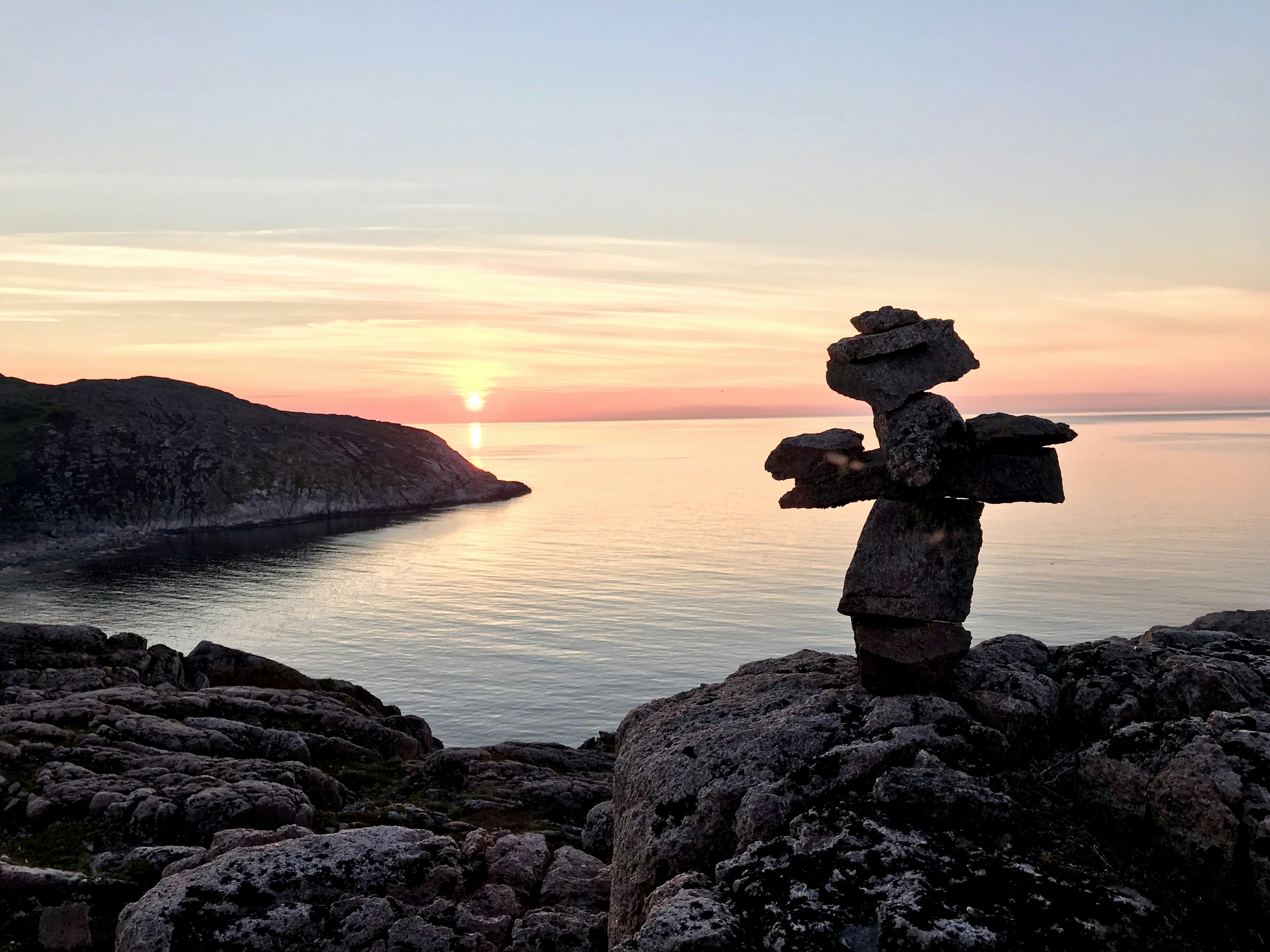 brown rock formation near body of water during sunset