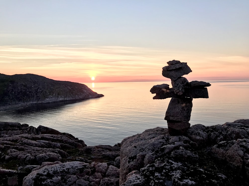 brown rock formation near body of water during sunset