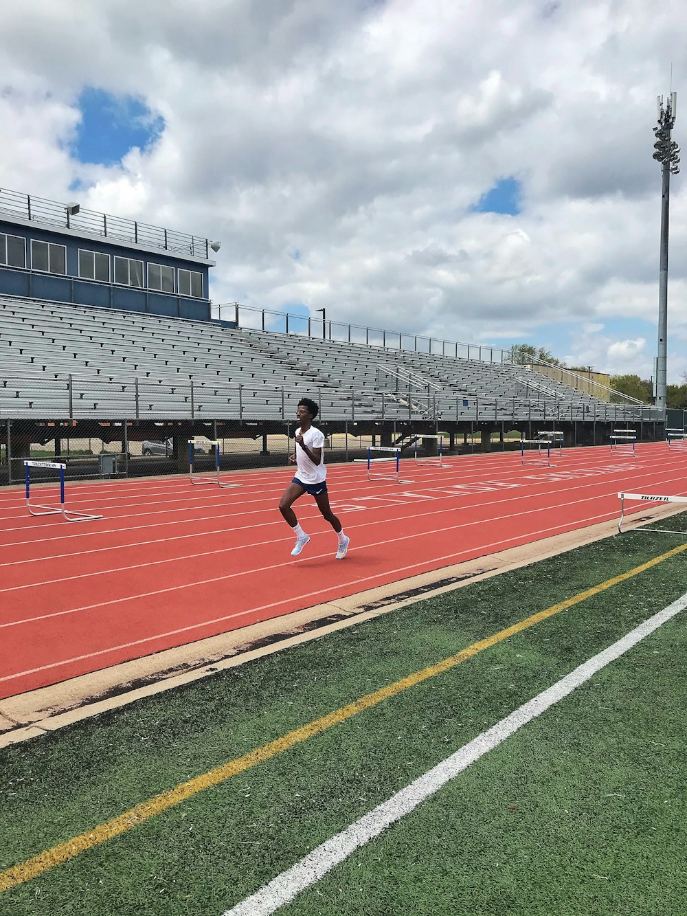 man in white shirt and black shorts running on track field during daytime