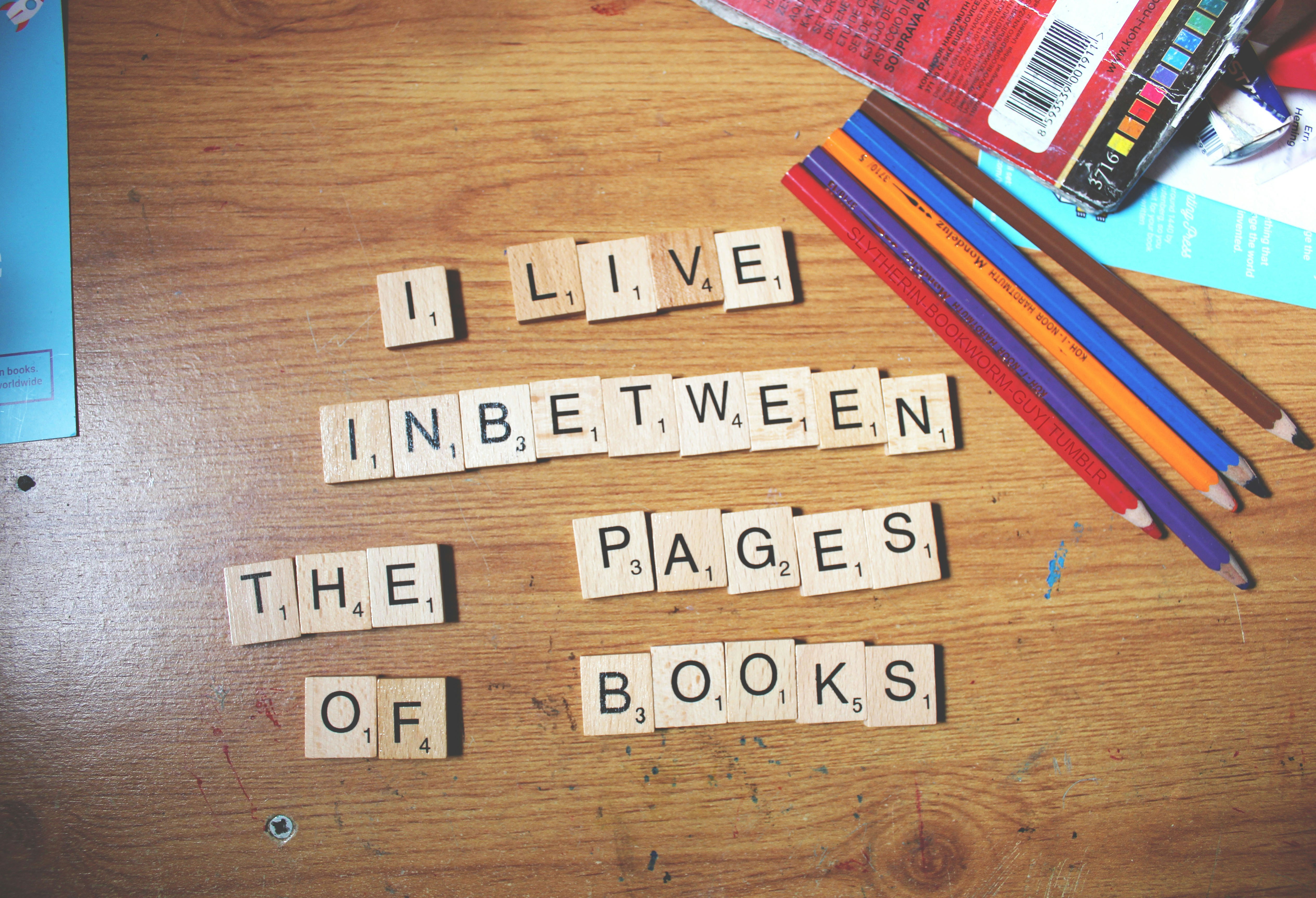 a wooden table topped with scrabble tiles and pencils