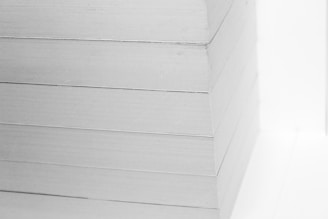 A close-up view of a neatly stacked pile of white paper sheets. The edges are perfectly aligned, creating a clean, precise visual appearance.