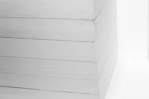A close-up view of a neatly stacked pile of white paper sheets. The edges are perfectly aligned, creating a clean, precise visual appearance.
