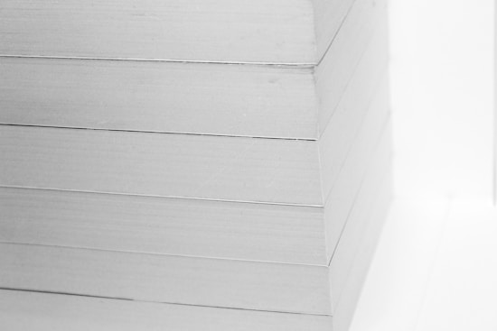 A close-up view of a neatly stacked pile of white paper sheets. The edges are perfectly aligned, creating a clean, precise visual appearance.