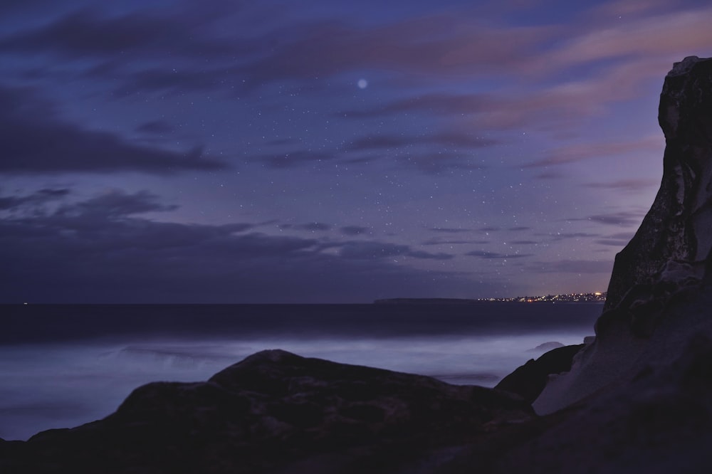 silhouette of mountain near body of water during night time