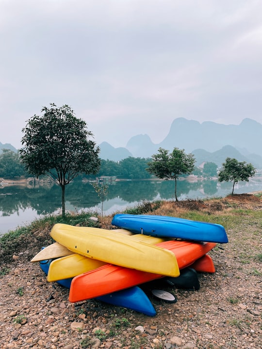 yellow and orange kayak on green grass field near body of water during daytime in Yangshuo China