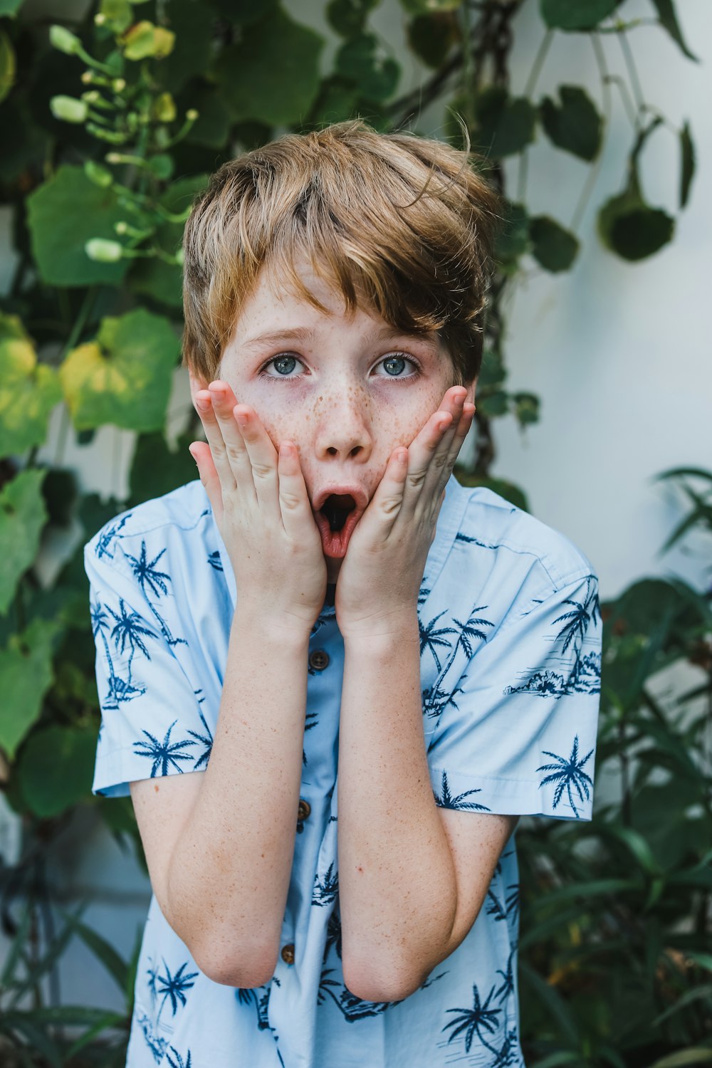 woman in white and blue floral shirt covering her mouth with her hand