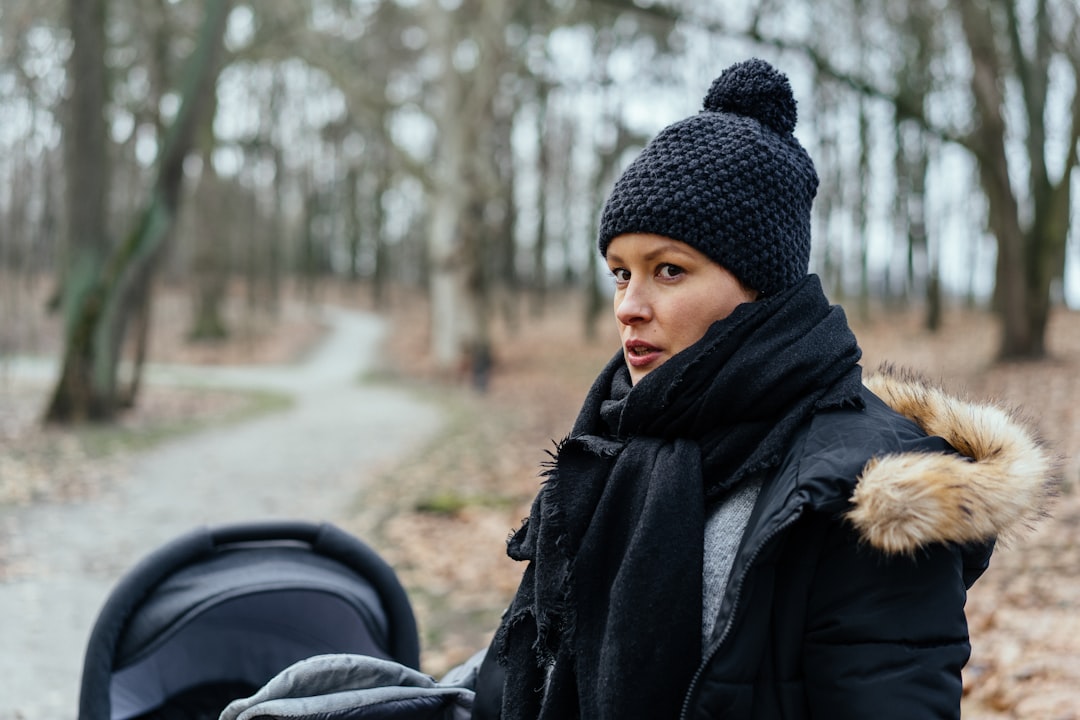 woman in black knit cap and black coat standing on road during daytime