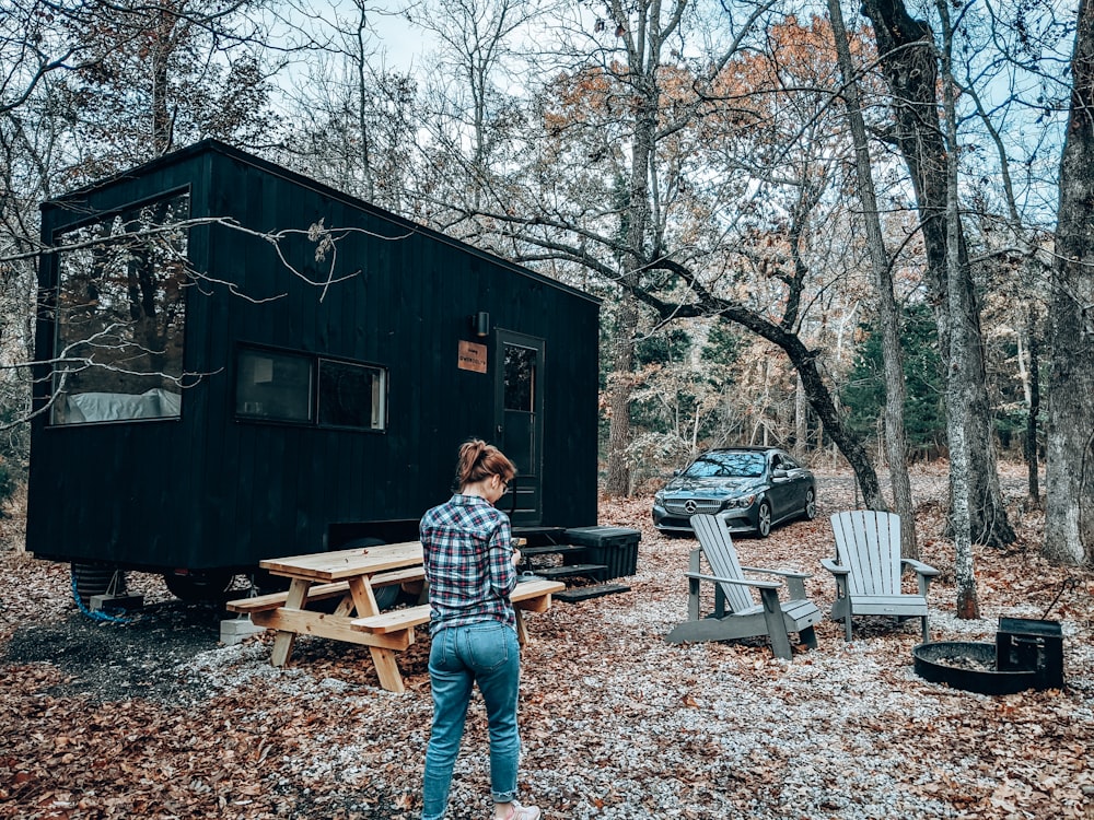 man in blue and white plaid dress shirt standing near brown wooden house during daytime