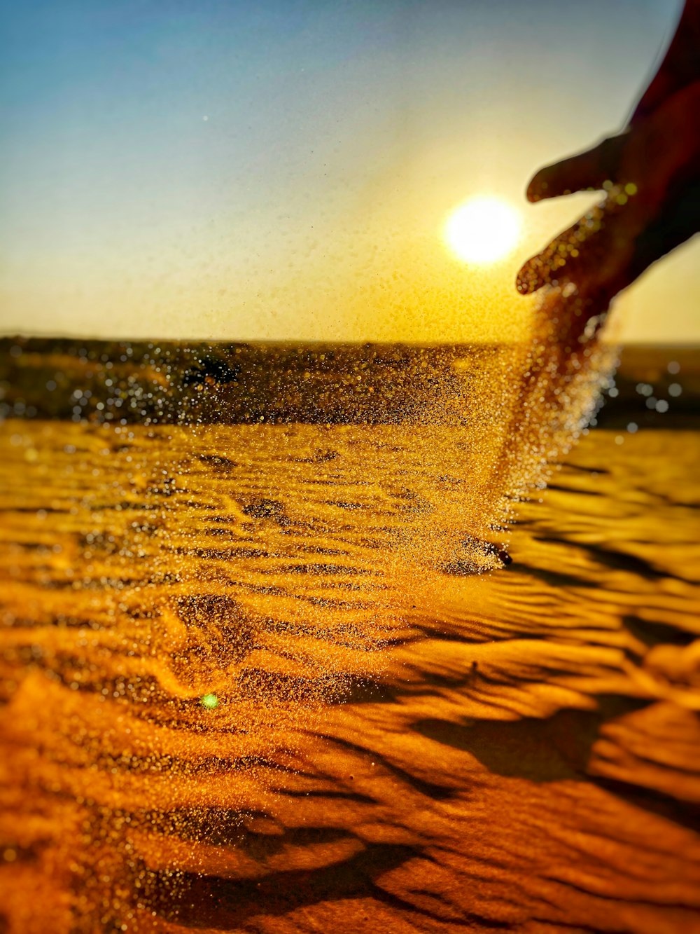 areia marrom perto do corpo de água durante o pôr do sol