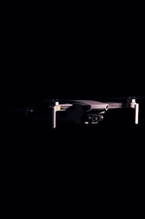 Close-up of a black DJI Mavic drone against a dark background, highlighting the camera and gimbal