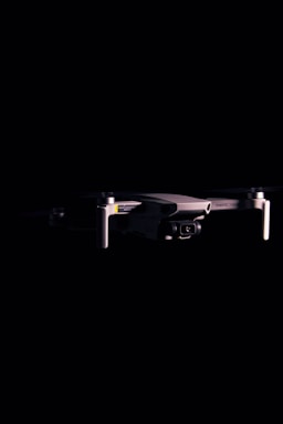 Close-up of a black DJI Mavic drone against a dark background, highlighting the camera and gimbal
