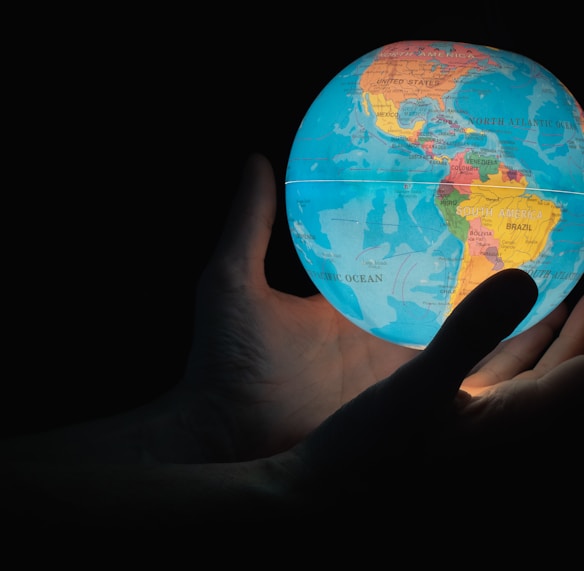 blue and brown globe on persons hand