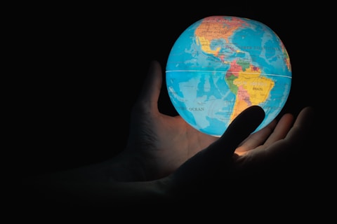 blue and brown globe on persons hand