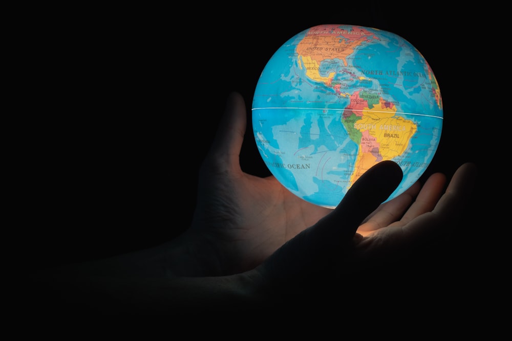 blue and brown globe on persons hand