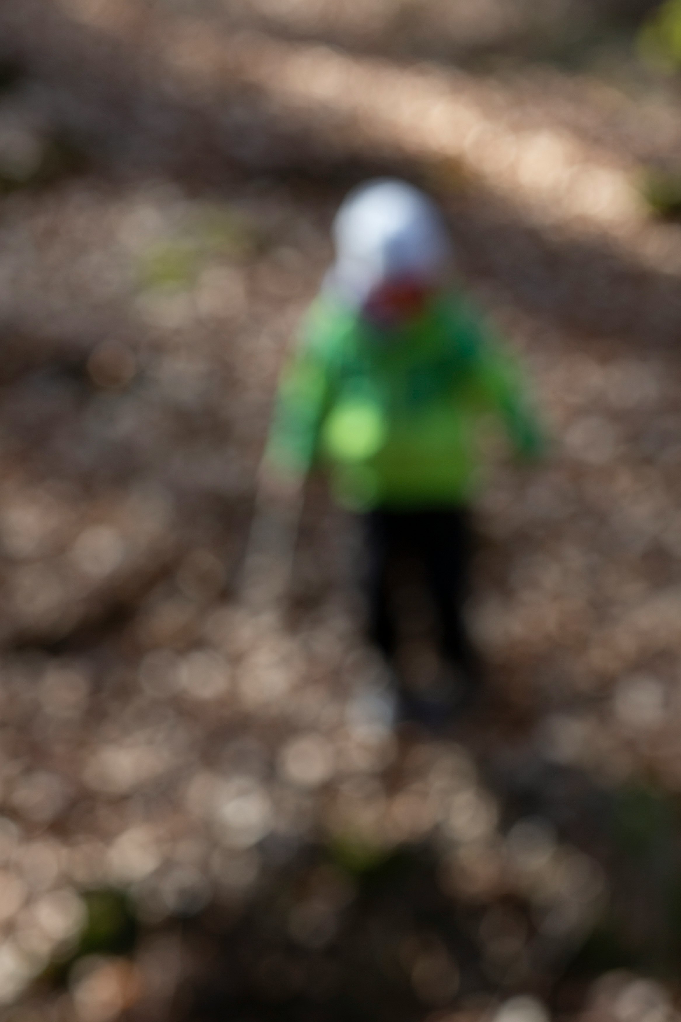 child in green jacket walking on dirt road during daytime
