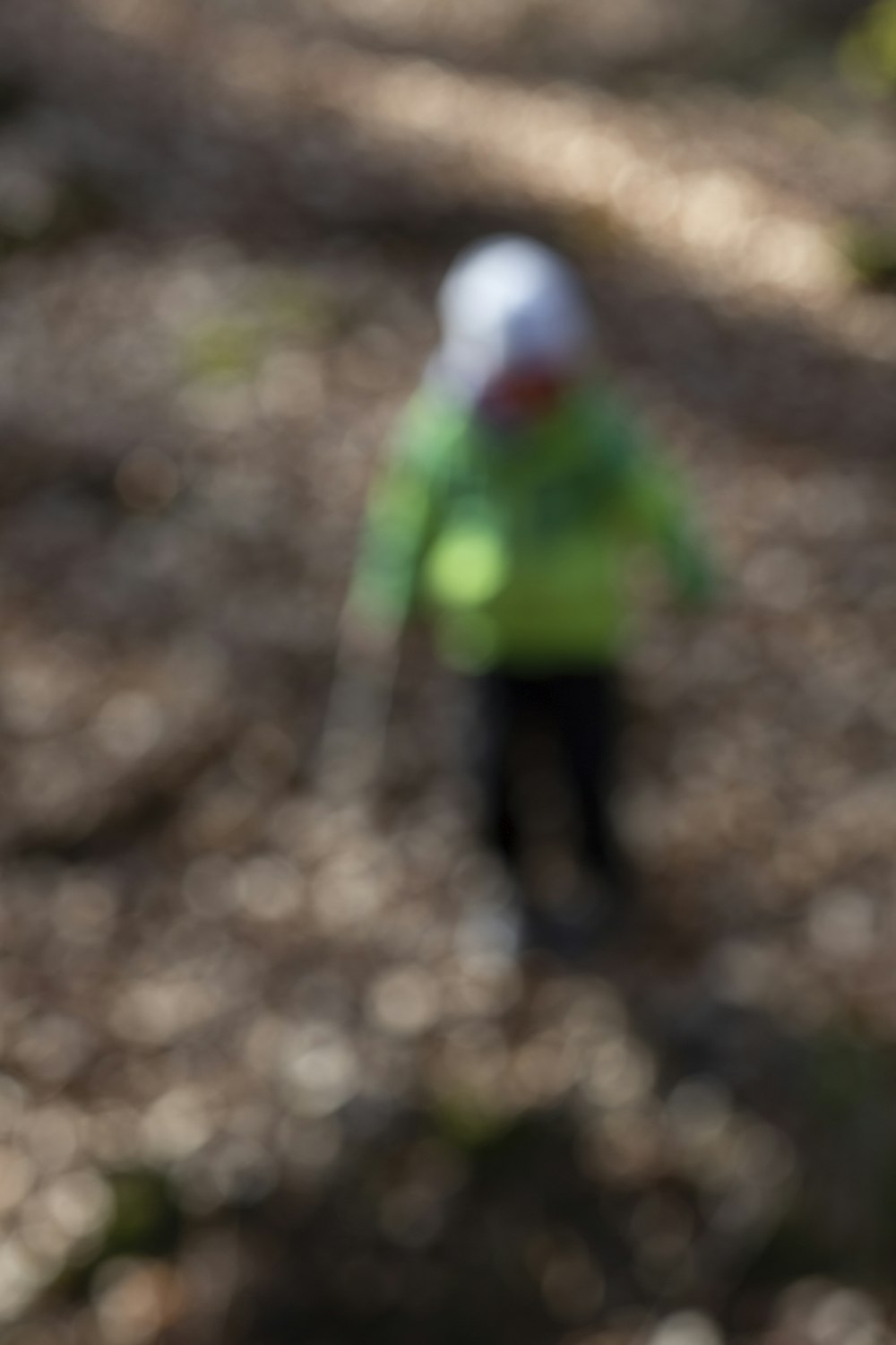 child in green jacket walking on dirt road during daytime