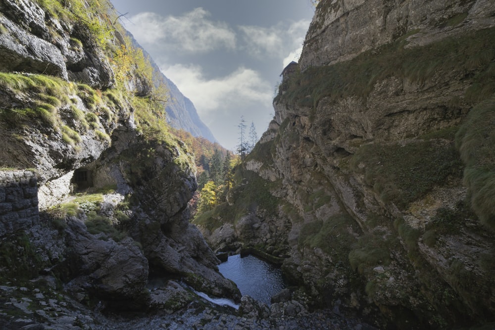 river between green and brown rocky mountains under white cloudy sky during daytime