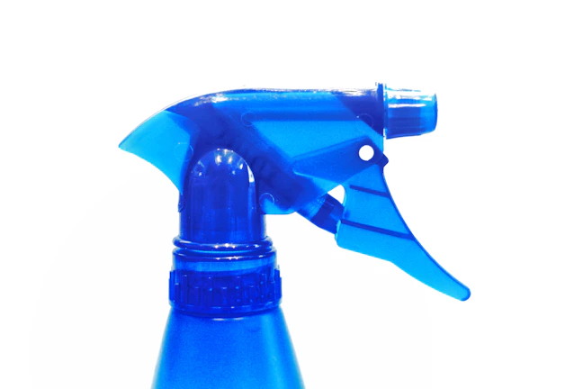 Close-up of a sparkling spray bottle with a fresh blue label against a white background.
