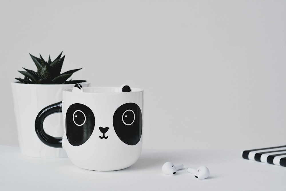 white and black ceramic mug beside apple earpods