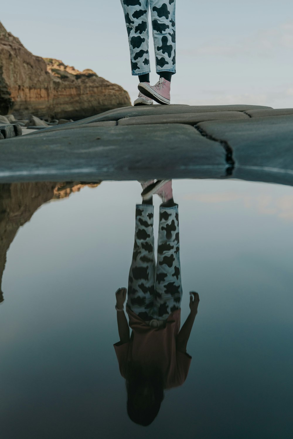 woman in black and white leopard print dress standing on brown wooden log during daytime