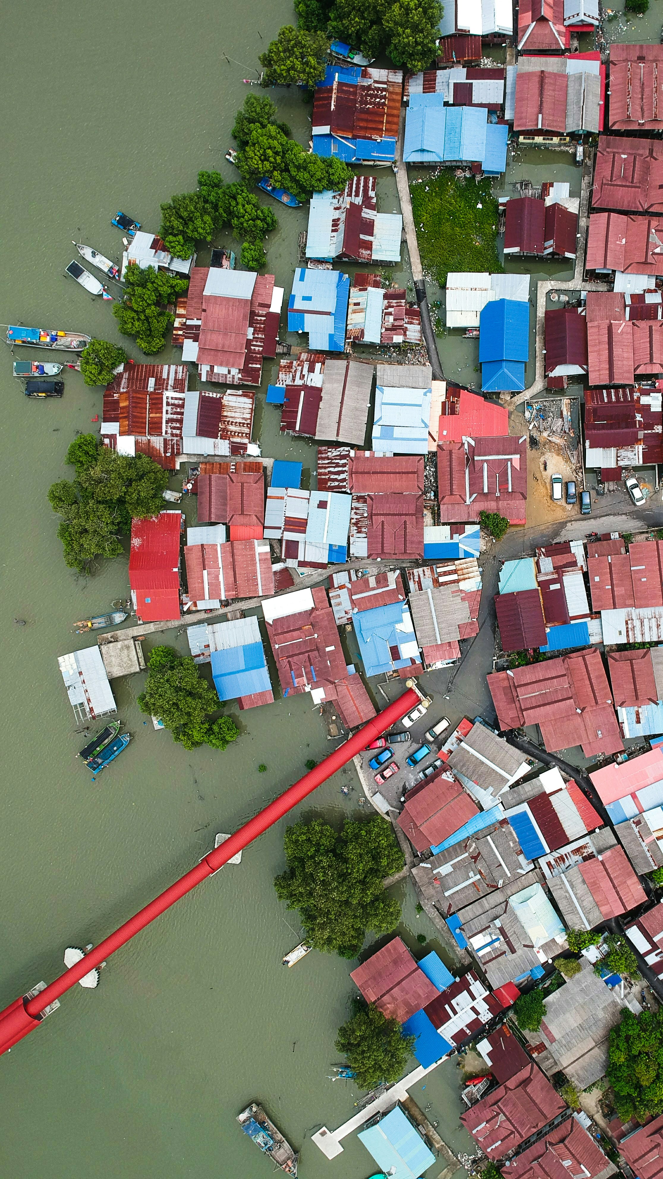 Aerial view of flooded village, rescue workers in boats, people on rooftops, grey skies