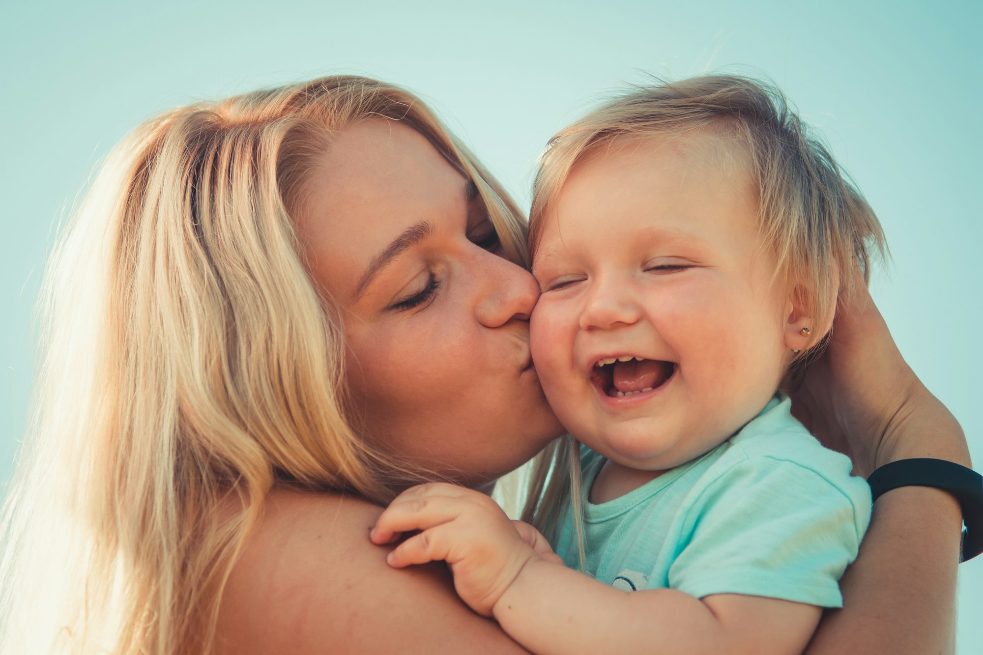 baby laughing, mother kissing baby