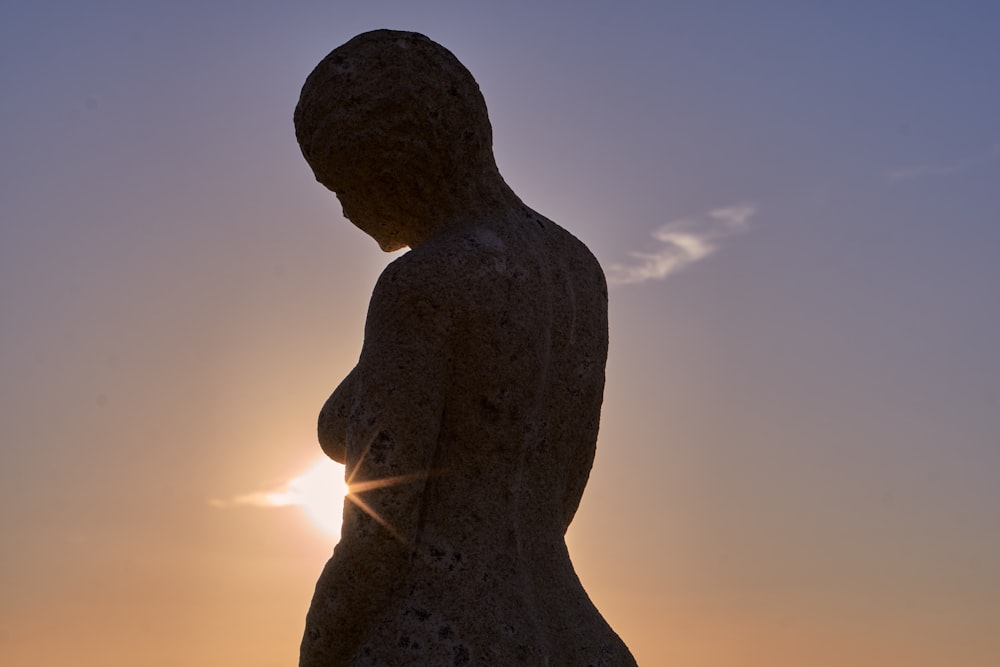 silhouette of man statue during sunset