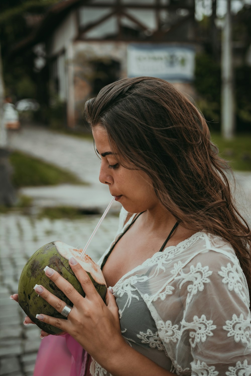 woman in white and red floral shirt holding green coconut