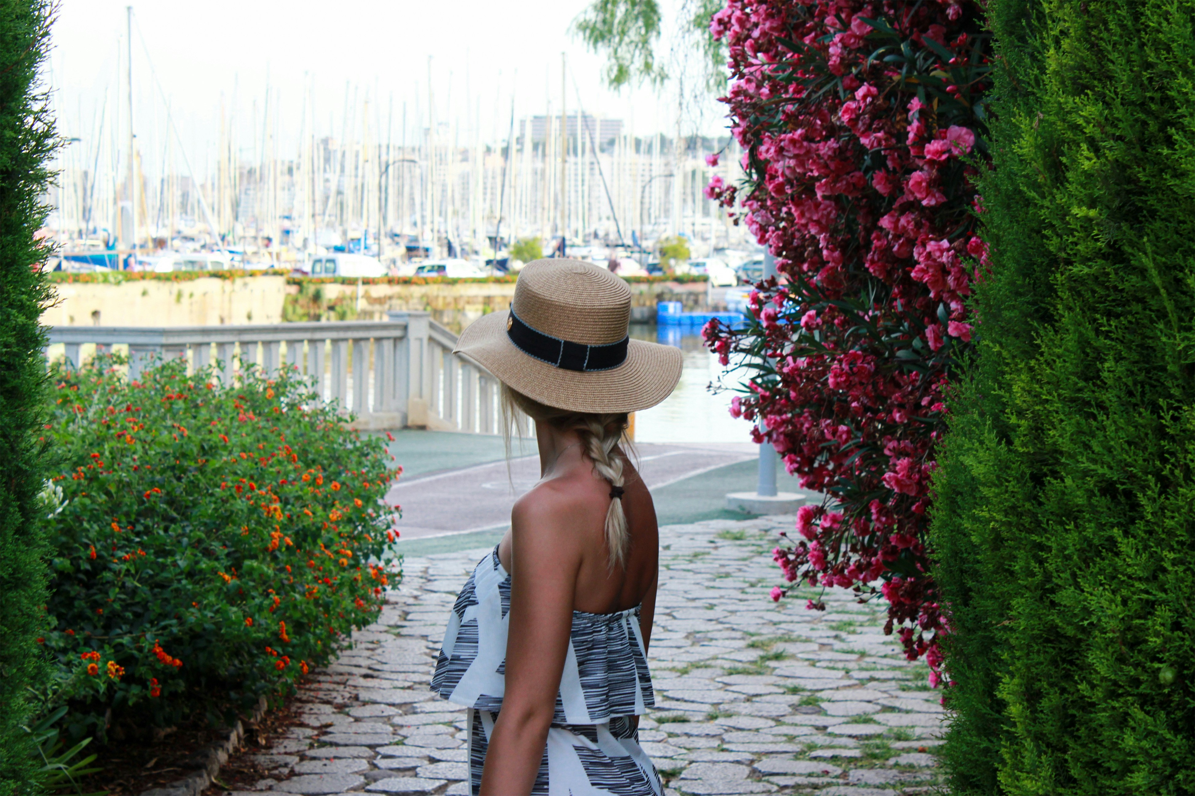 the girl with hat is looking at the dock with yachts