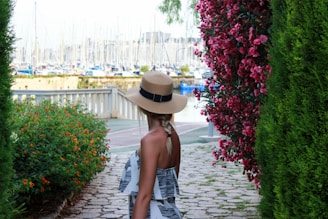 woman in black and white dress wearing brown hat standing on pathway during daytime