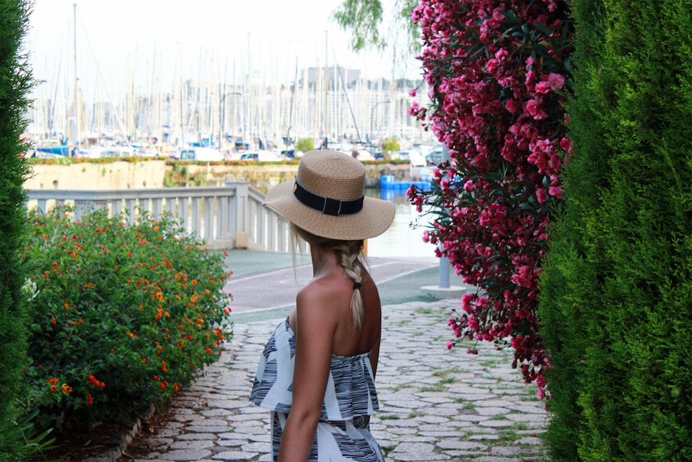 woman in black and white dress wearing brown hat standing on pathway during daytime