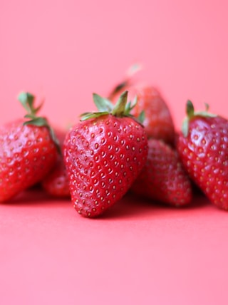 red strawberries on pink surface