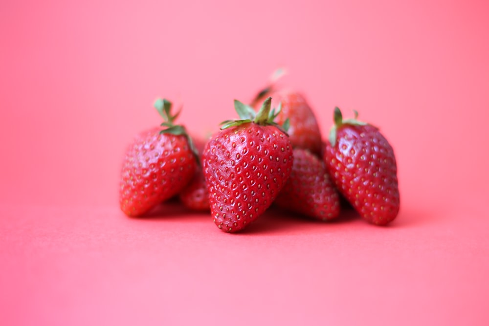 red strawberries on pink surface