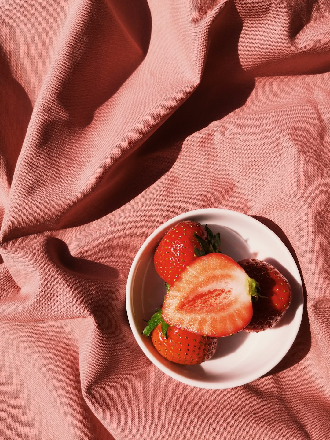  sliced strawberry and blackberry in white ceramic bowl tablecloth