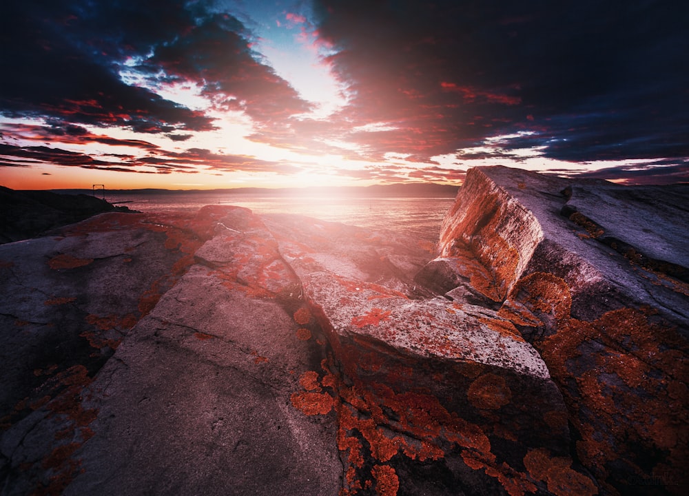 brown rock formation near sea during sunset